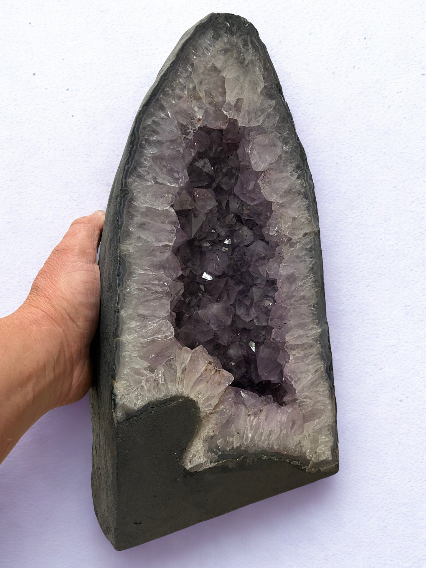 Amethyst geode held by a hand on a white background
