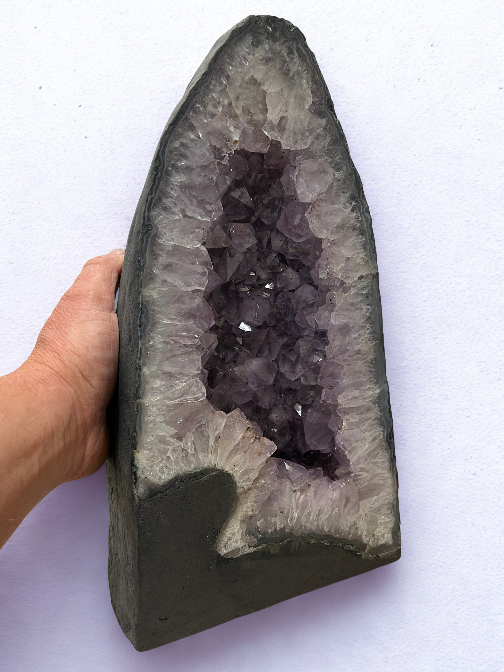 Amethyst geode held by a hand on a white background