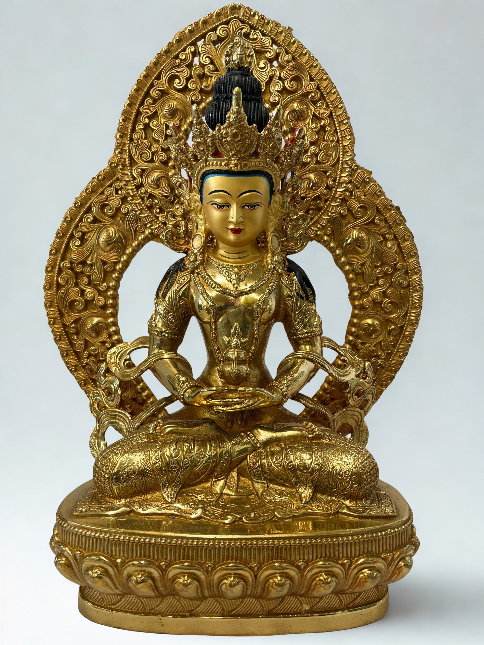Gold-colored Amitayus Buddha statue with intricate designs on a white background