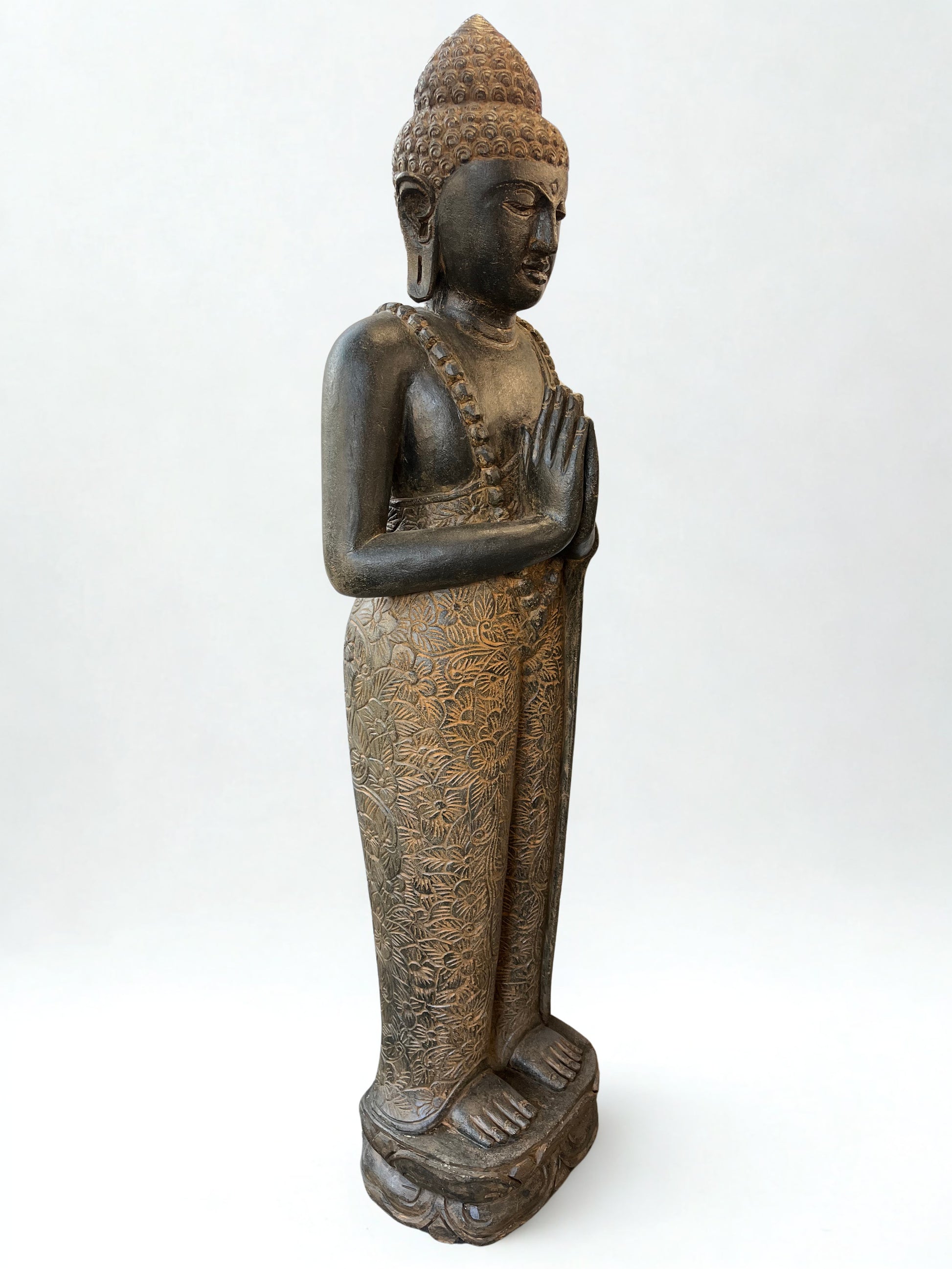 Bronze statue of a standing Buddha on a white background