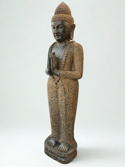 Statue of a standing meditating Buddha figure in namaste pose on a white background