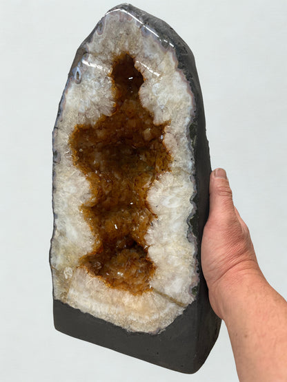 Geode crystal held by a hand against a light gray background