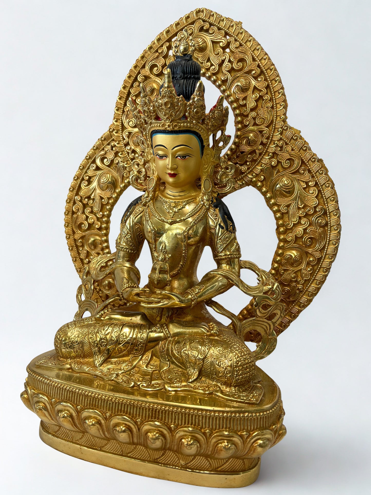 Gold-colored Amitayus Buddha statue with intricate designs on a white background
