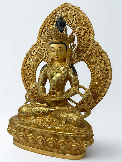Gold-colored Amitayus Buddha statue with intricate designs on a white background