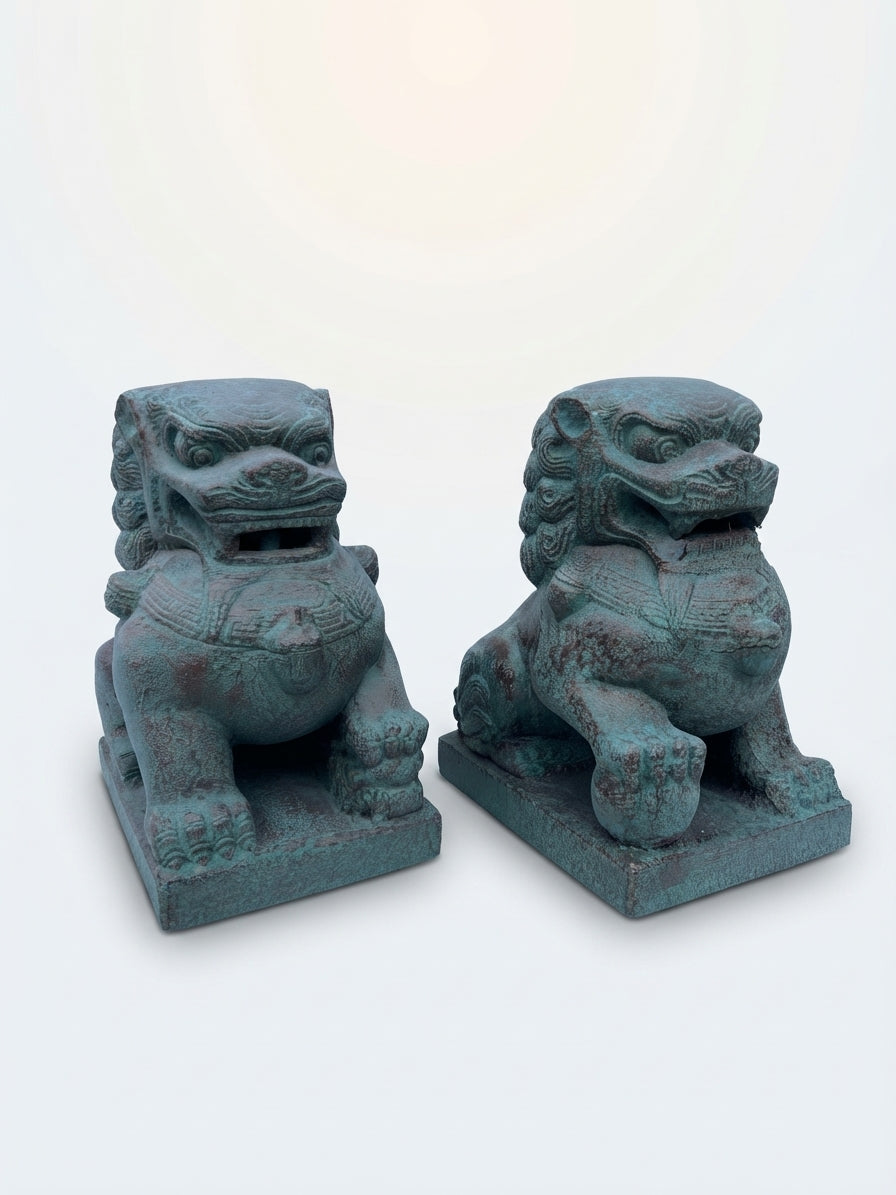 A pair of traditional Chinese stone lion statues with a weathered teal-green patina, displayed side-by-side on a clean white background.