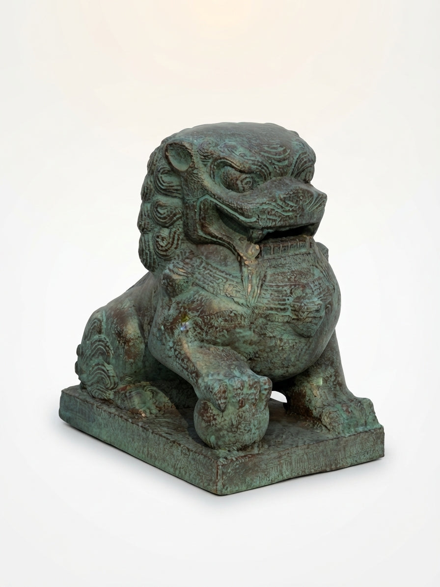 A traditional Chinese bronze-finished stone lion statue with a verdigris patina, sitting on a rectangular base against a plain white background.