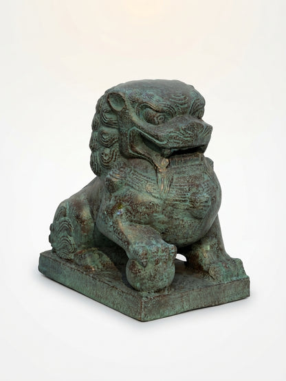 A traditional Chinese bronze-finished stone lion statue with a verdigris patina, sitting on a rectangular base against a plain white background.