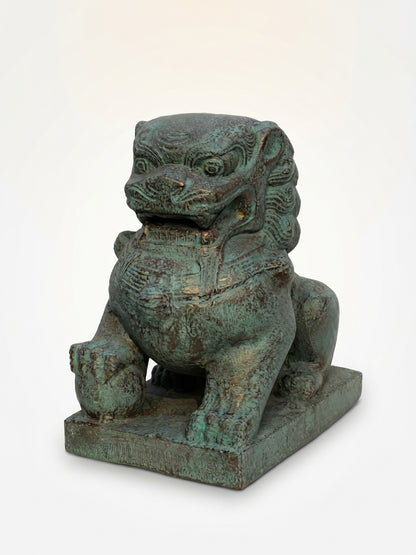 A traditional Chinese bronze-finished stone lion statue with a verdigris patina, sitting on a rectangular base against a plain white background.