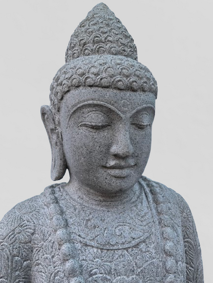 Stone statue of a Buddha with intricate details on a light gray background