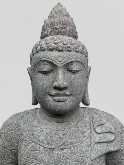 Stone statue of a Buddha with intricate details on a plain background