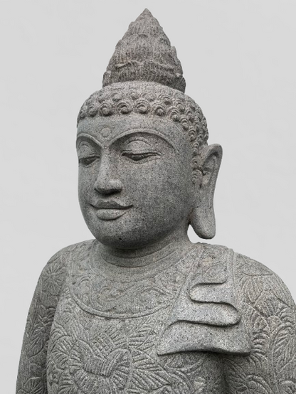 Stone statue of a Buddha figure with intricate details on a light gray background