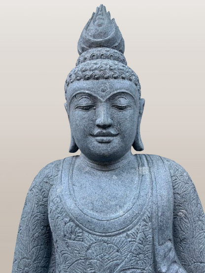 Stone statue of a seated Buddha with intricate details on a beige background