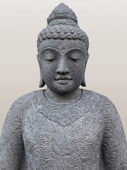 Stone statue of a Buddha figure with intricate carvings on a plain background