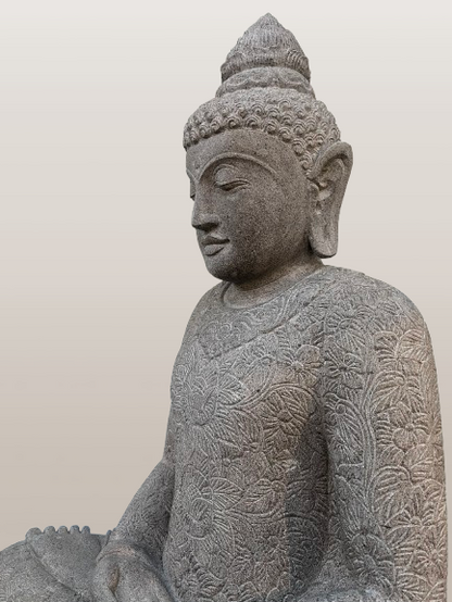 Stone statue of a seated Buddha with intricate patterns on a plain background