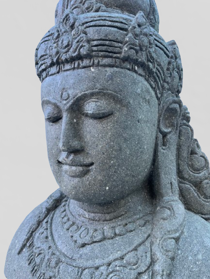 Stone sculpture of a goddess  face with intricate details on a plain background