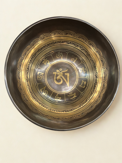 Decorative singing bowl with gold and black design on a beige background