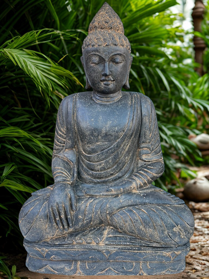 Stone Buddha statue in a garden setting with greenery