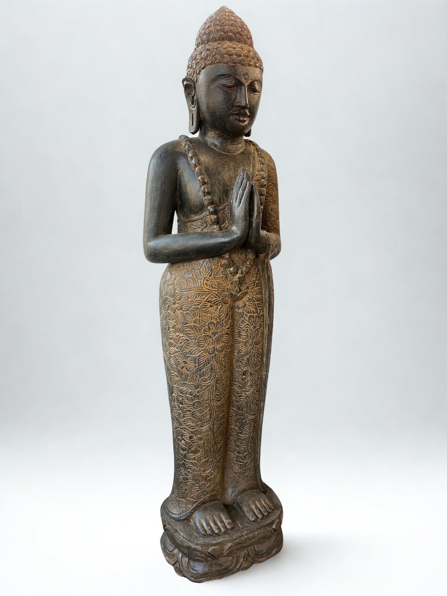 Bronze statue of a standing Buddha on a white background