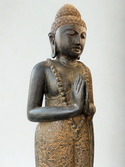 Bronze statue of a standing Buddha with intricate details on a white background