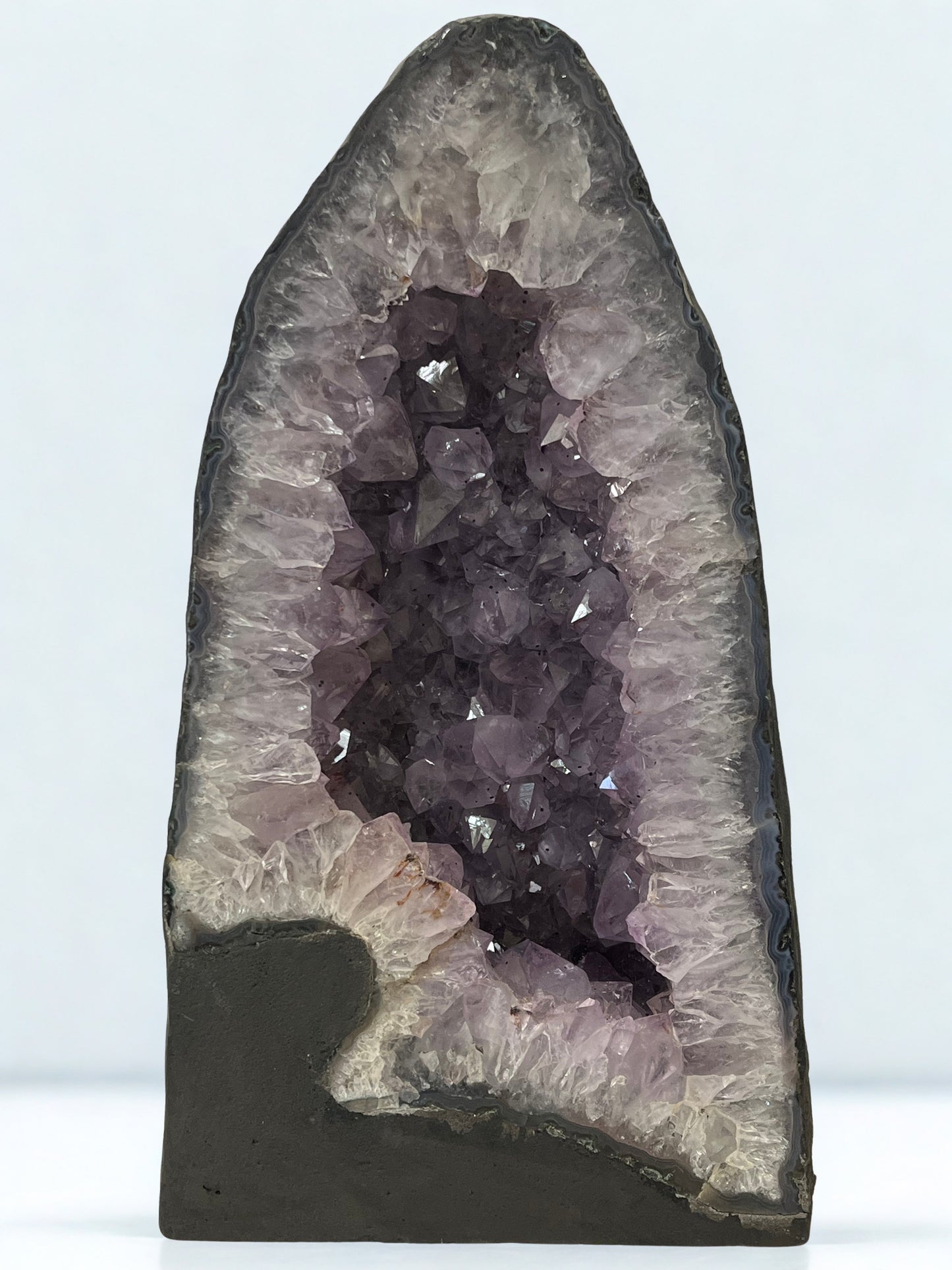 Amethyst crystal formation in a dark gray geode against a white background