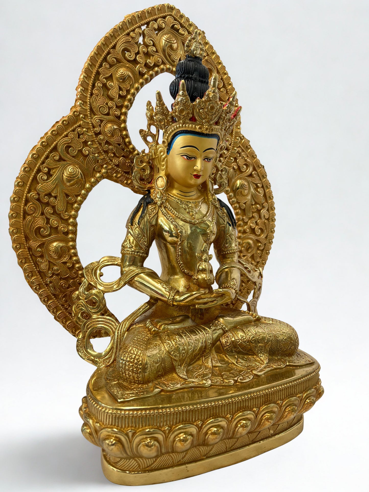 Gold-colored Amiayus Buddha statue with intricate designs on a white background