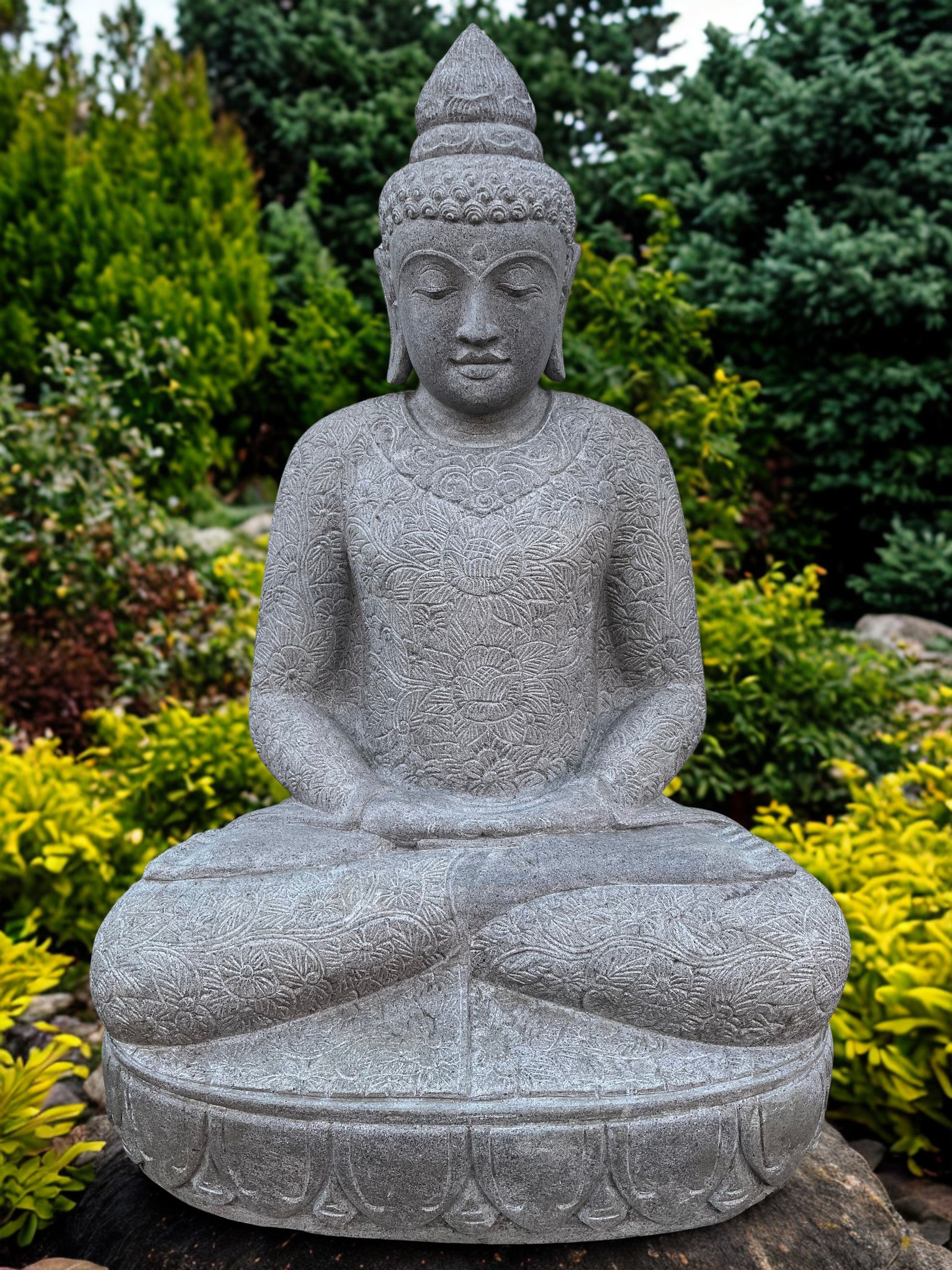 Stone Buddha statue in a garden setting with greenery