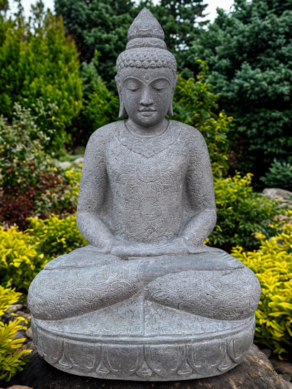 Stone Buddha statue in a garden setting with greenery