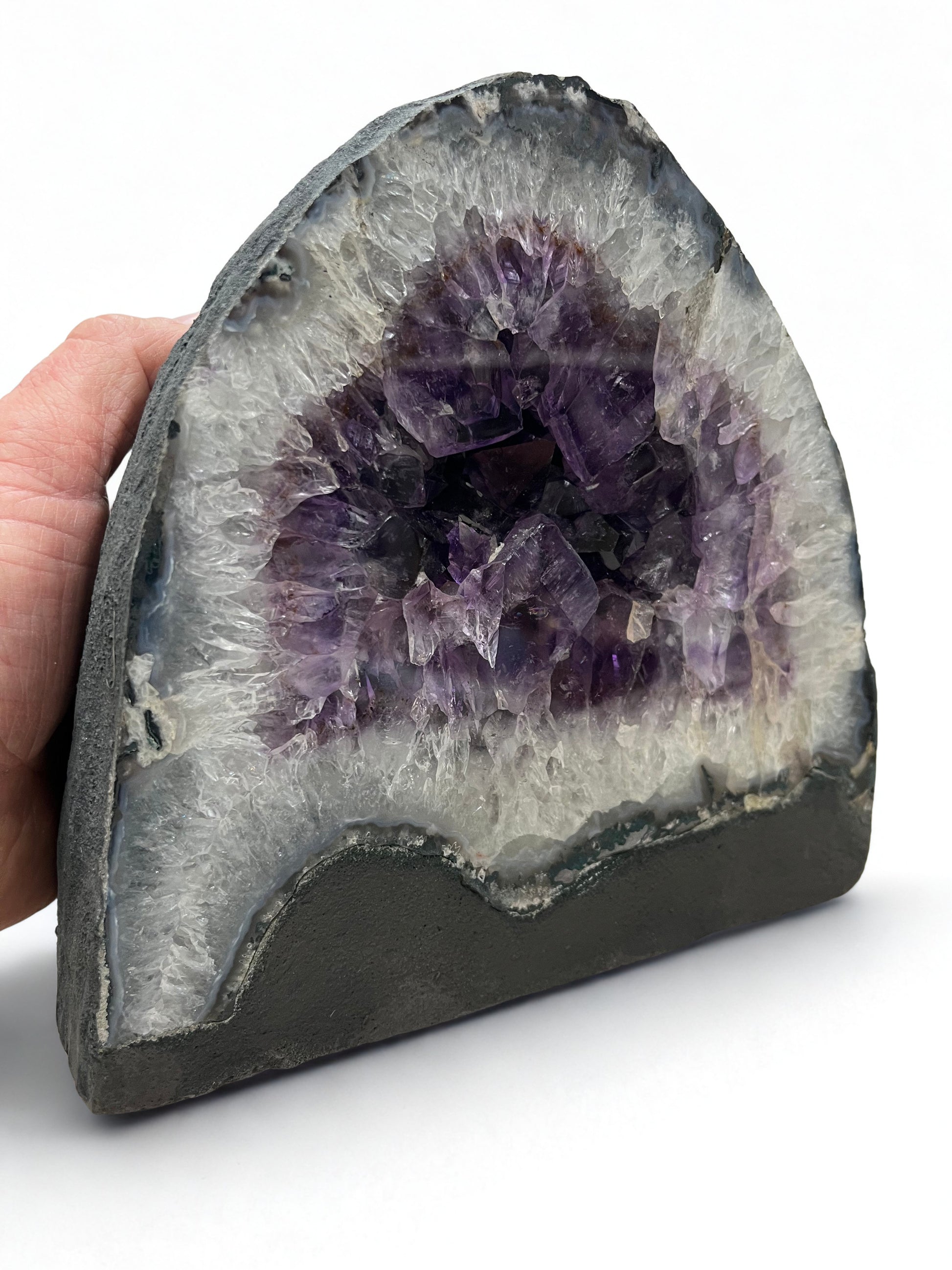 Amethyst geode held by a hand on a white background